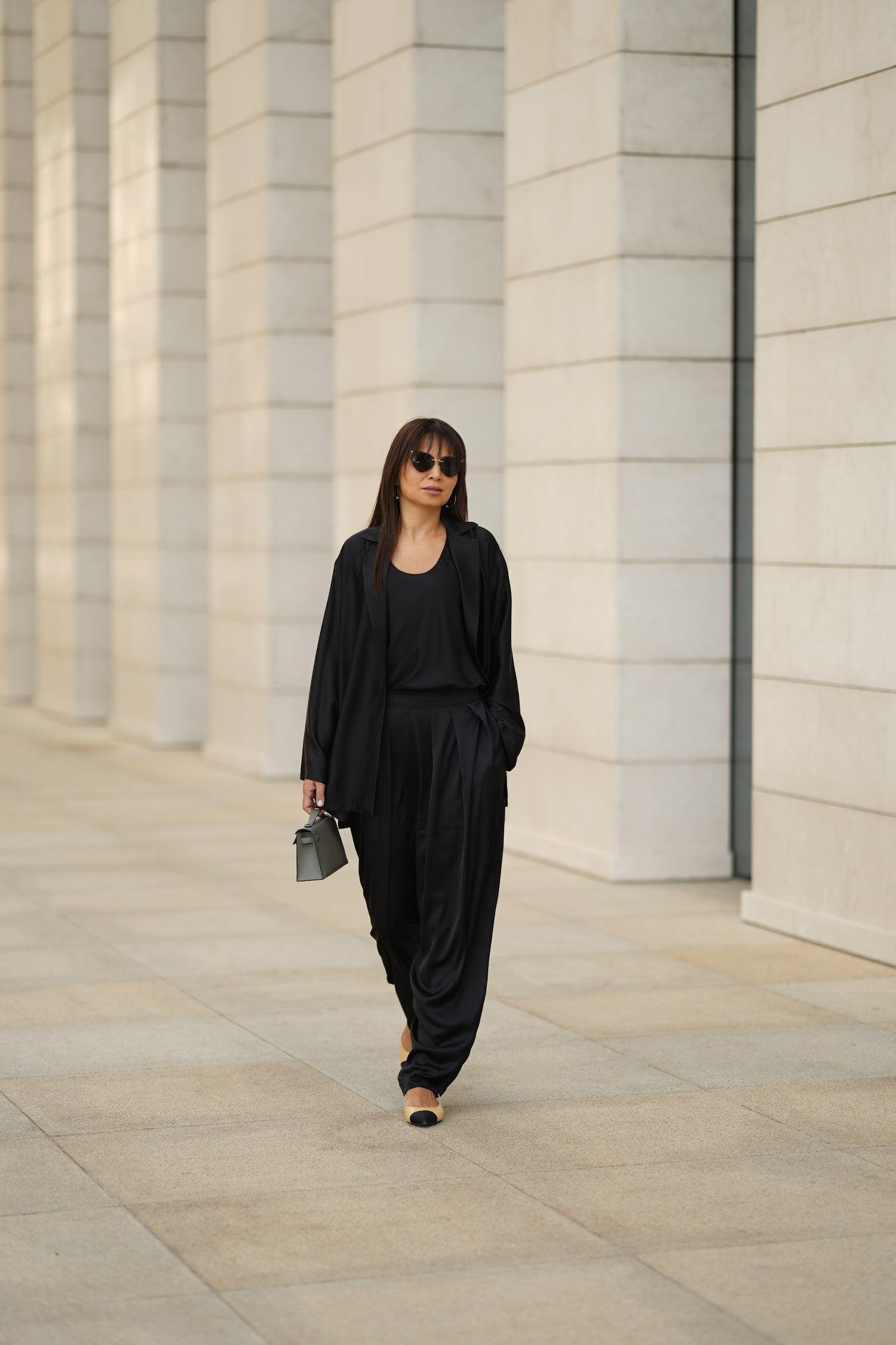 Woman in a black outfit walking in an architectural setting